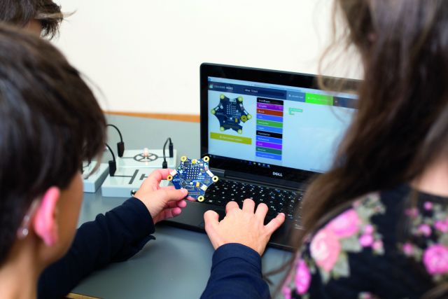 Schüler programmieren an einem Laptop.