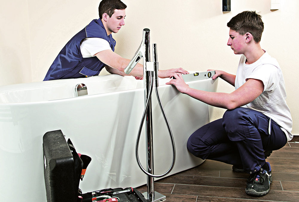 Zwei SHK-Handwerker installieren eine Badewanne