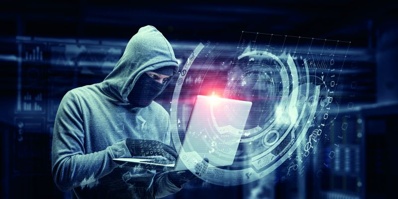 Ein professioneller Hacker stiehlt personenbezogene Daten an einem Laptop. Dies ist die Folge von nicht ausreichenden Datenschutz.