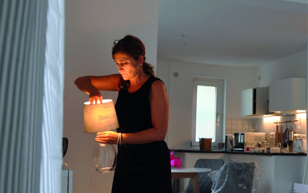 Frau stellt eine Lampe in eine Küche (Home Stager)